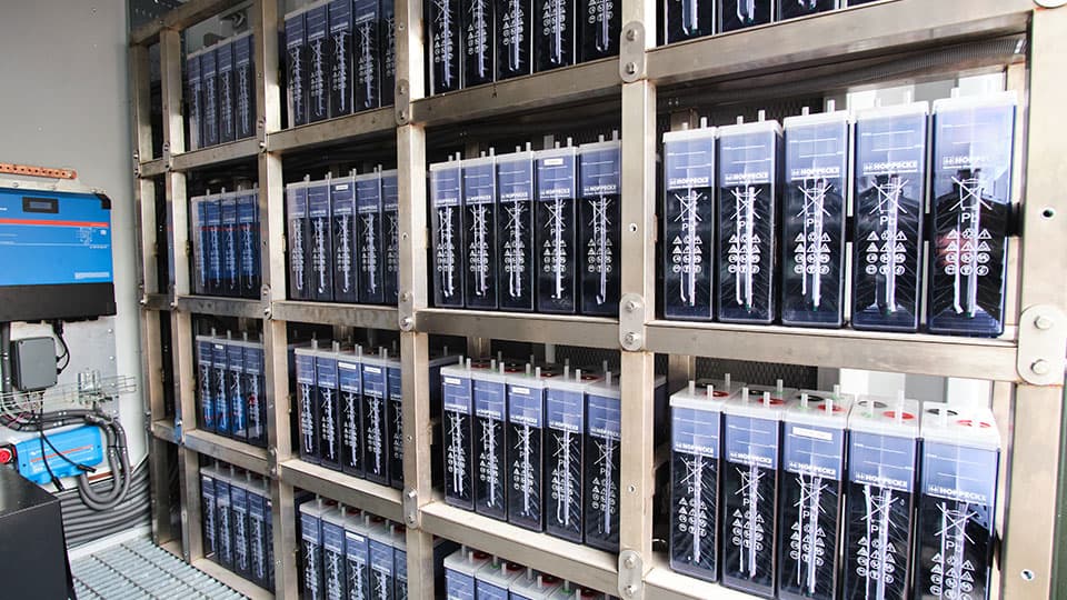 A trailer unit holding multiple batteries with labels and a blue liquid